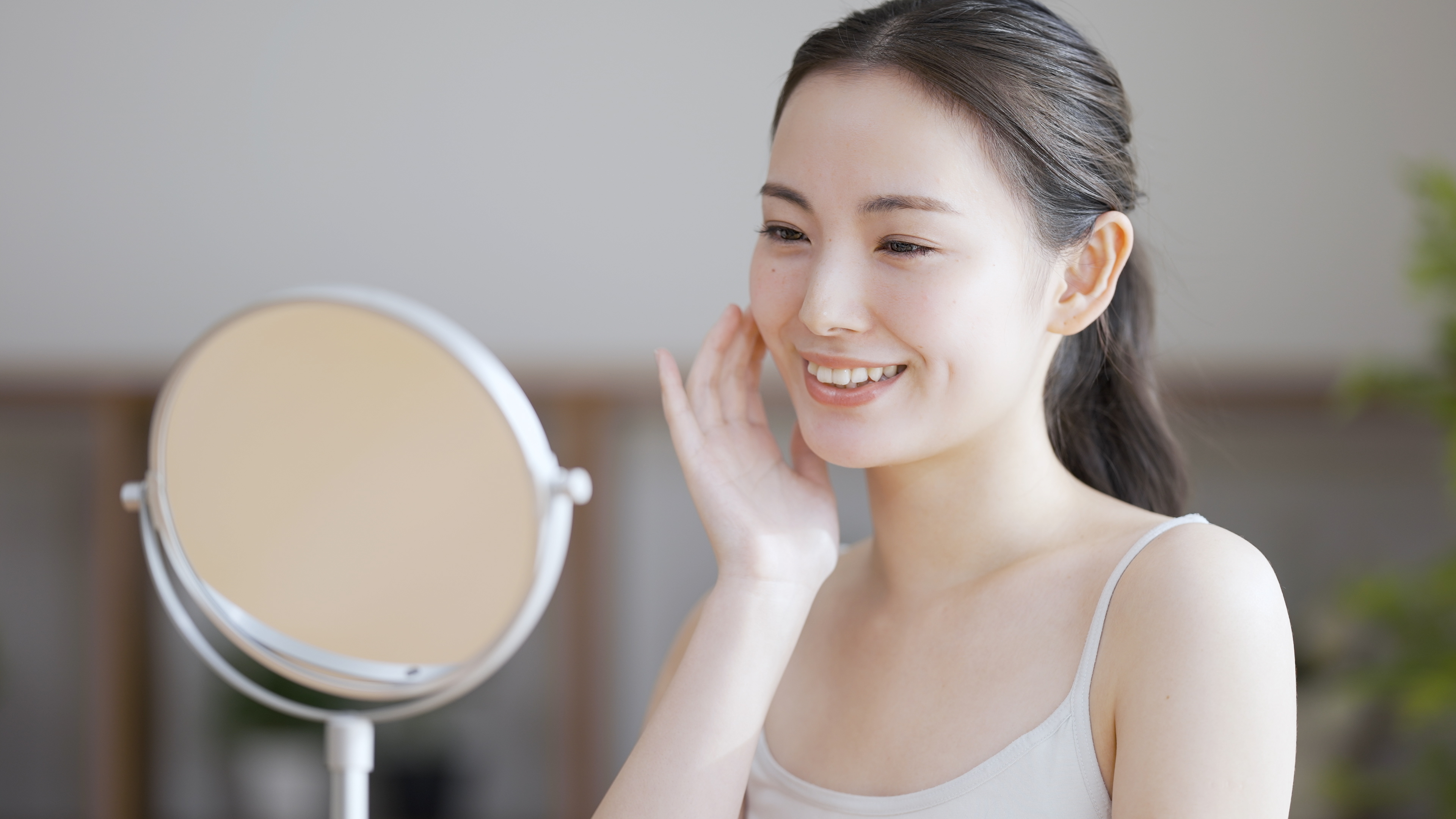 young woman looking in mirror after chemical peel treatment 